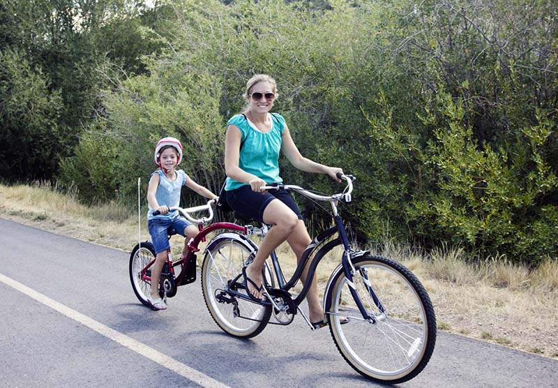 mom and son riding on tandem bike with tree landscape in background