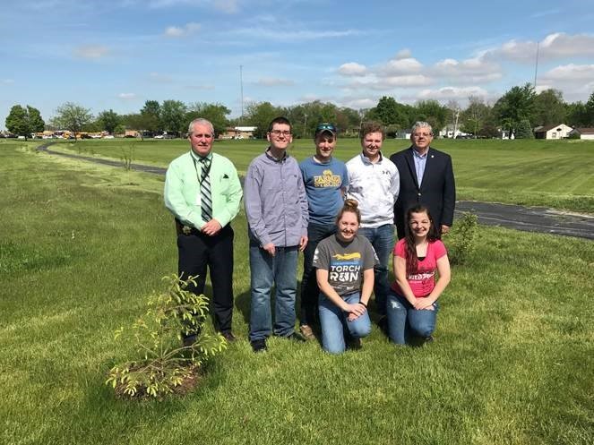 Police Chief Jim Phelps, Mayor Paul Schore, and five bradley-bourbonnais community high school students in park field where trees were planted